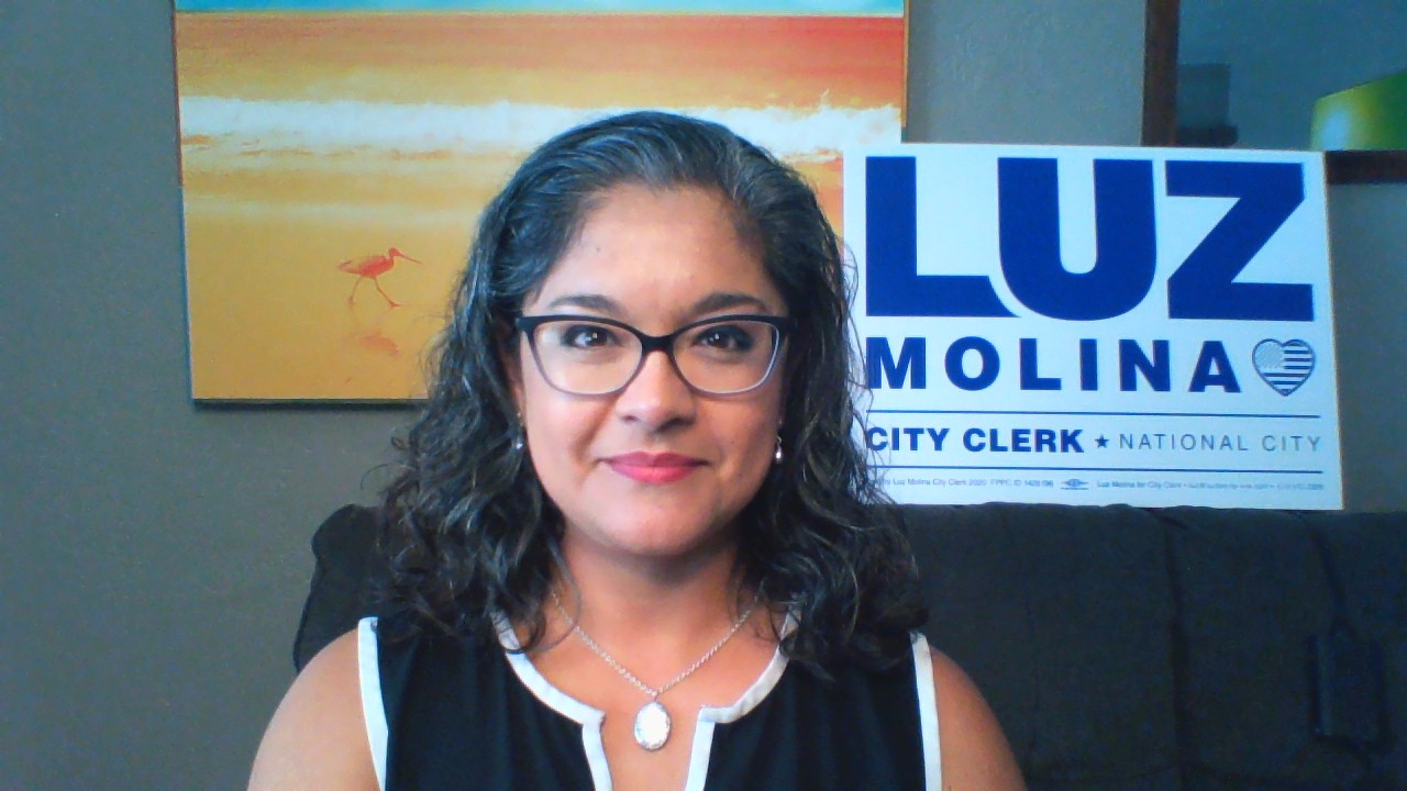 Luz standing next to election sign